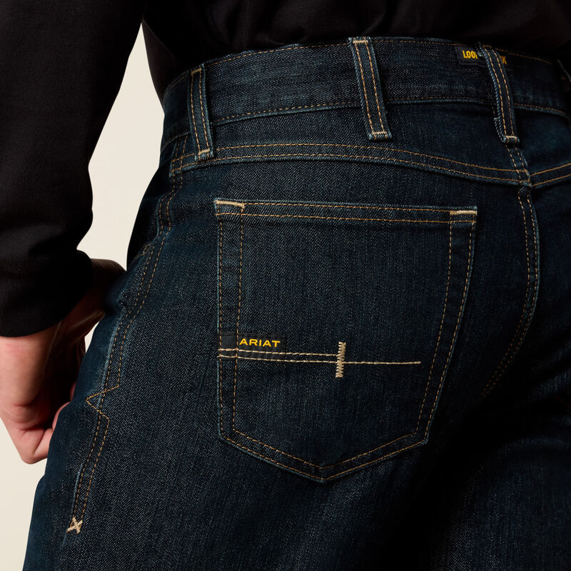 Men's Ariat Rebar M7 slim straight work jeans, in Blackstone a dark wash. Rear view showing back pocket stitching with Ariat logo. Also shows side stitching and anchored belt loops.