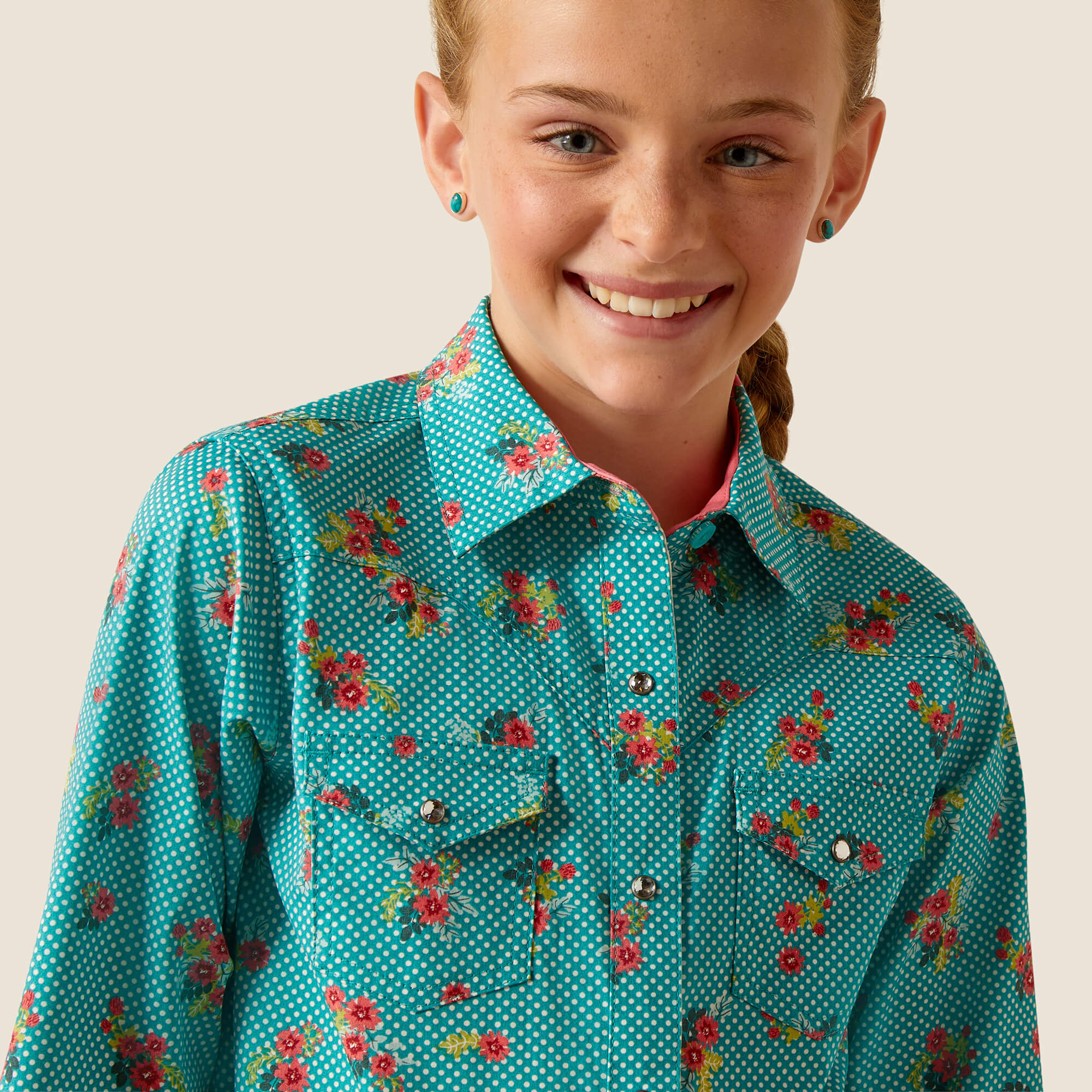 Girl's Ariat long sleeve western style shirt in a dotted Green with a floral print. Close up view of front showing jeweled snaps and chest pockets.