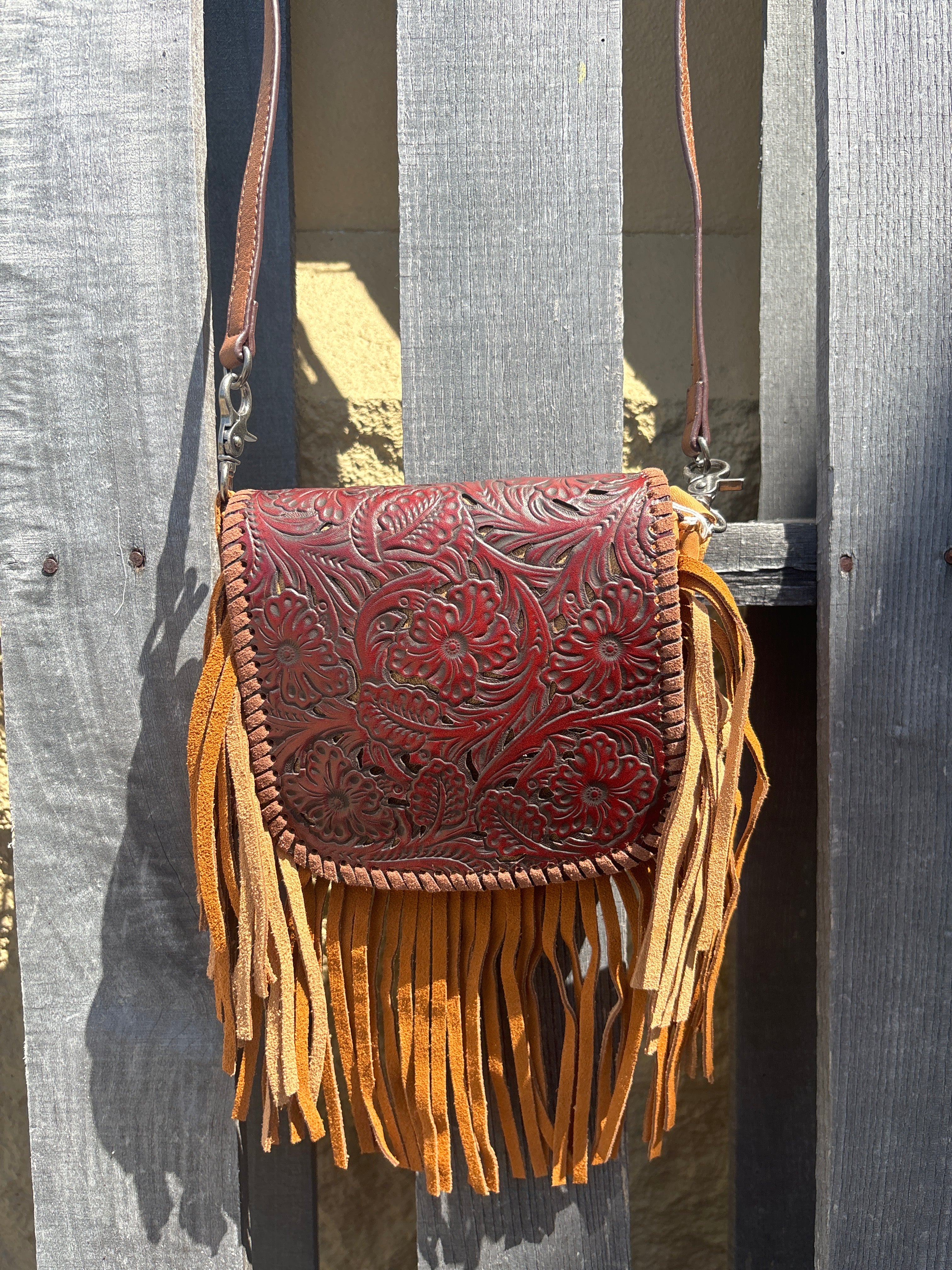 This Brown tooled leather and fringe crossbody bag has a removable and adjustable strap. Front view