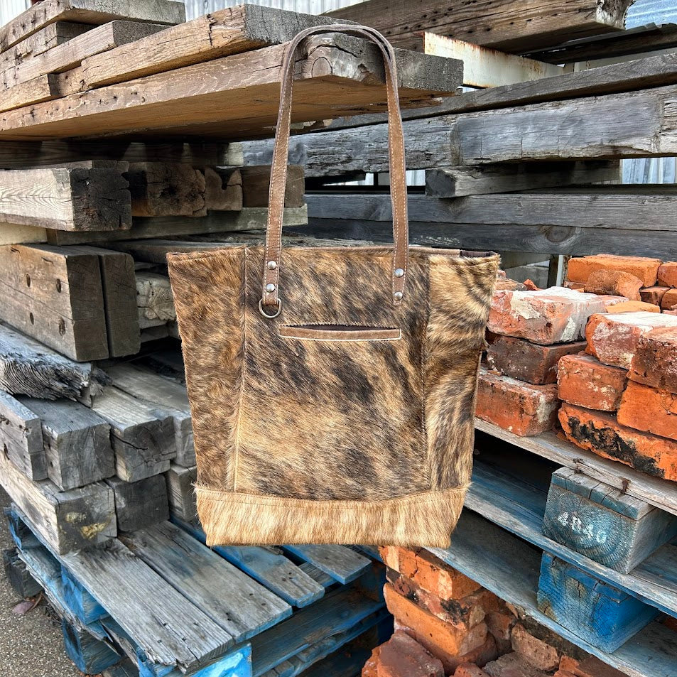 Brown leather and cowhide tote bag with a solid leather back with a concealed carry pocket. Front View A