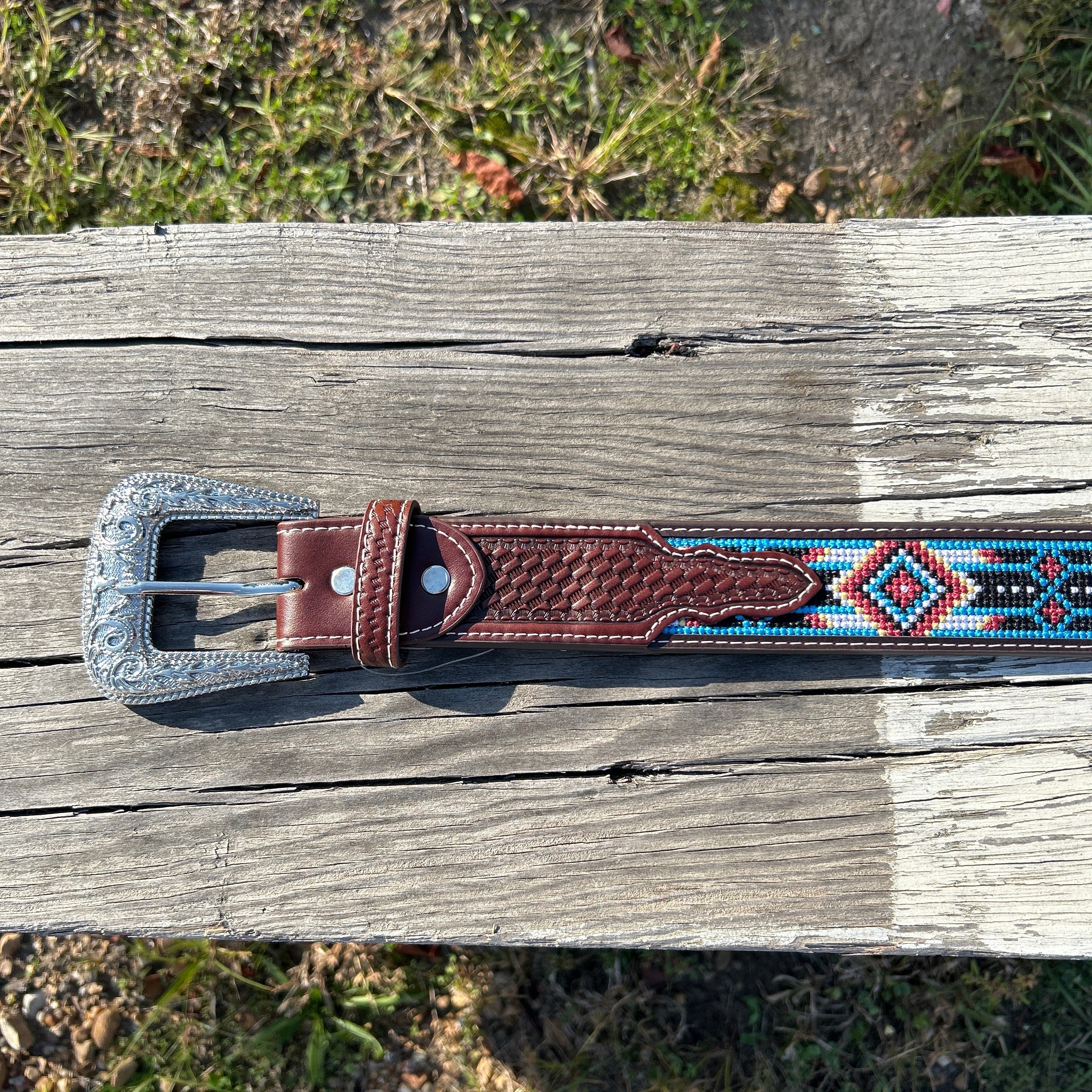 This Red and Blue embroidered belt has a basketweave leather overlay on each end with a matching keep. The Silver buckle has a intricate design featuring a Longhorn. Close up view of buckle and keep.