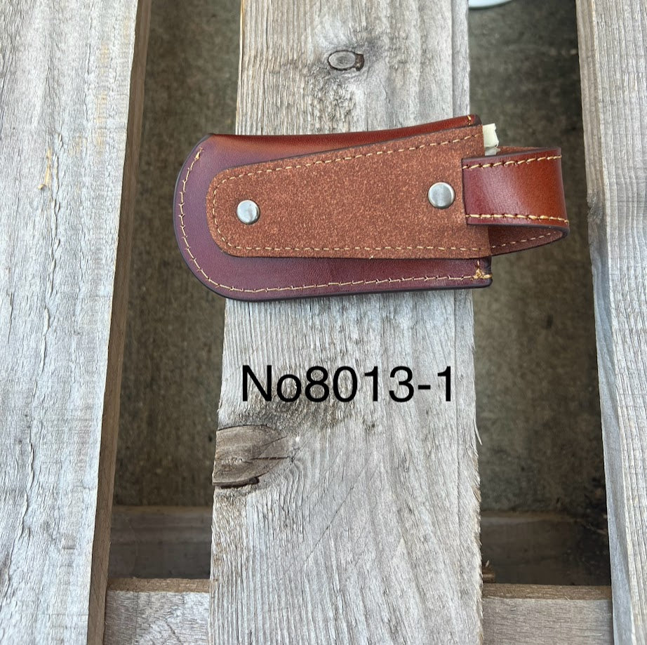 A brown leather knife sheath with a embossed Praying Cowboy. Rear view showing belt loop.