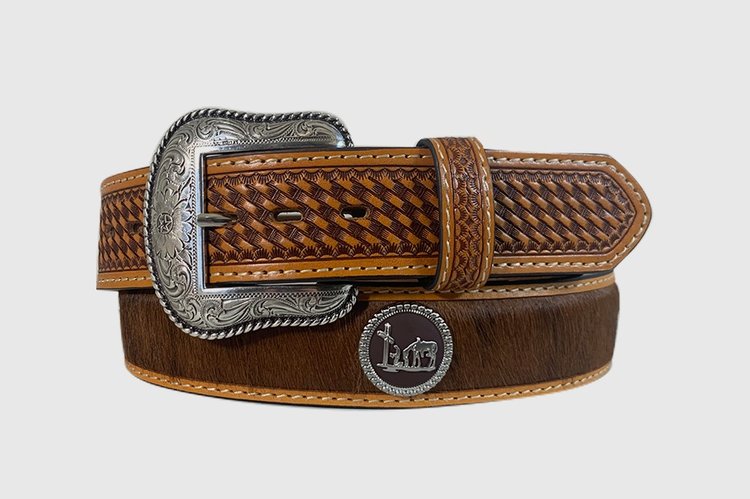 A brown leather belt with a basketweave pattern and a silver finish buckle featuring a cowhide design. Concho with praying cowboy figuring.