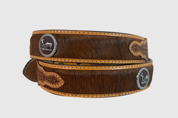 A brown leather belt with a basketweave pattern and hair-on design. Concho with praying cowboy figuring.