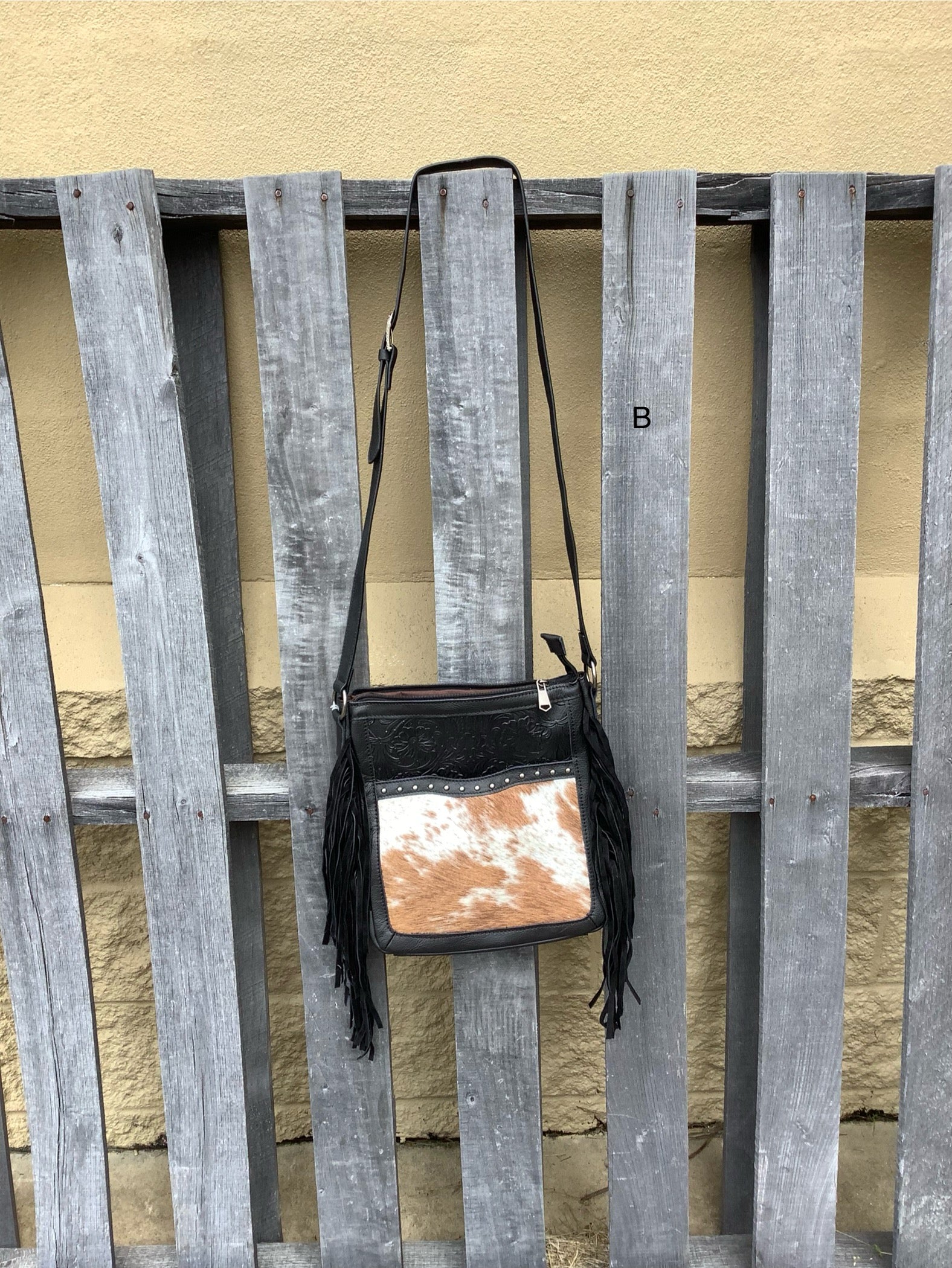 This Black leather and cowhide bag has side fringe and a tooled leather design. It has a rear concealed carry pocket. Front View B