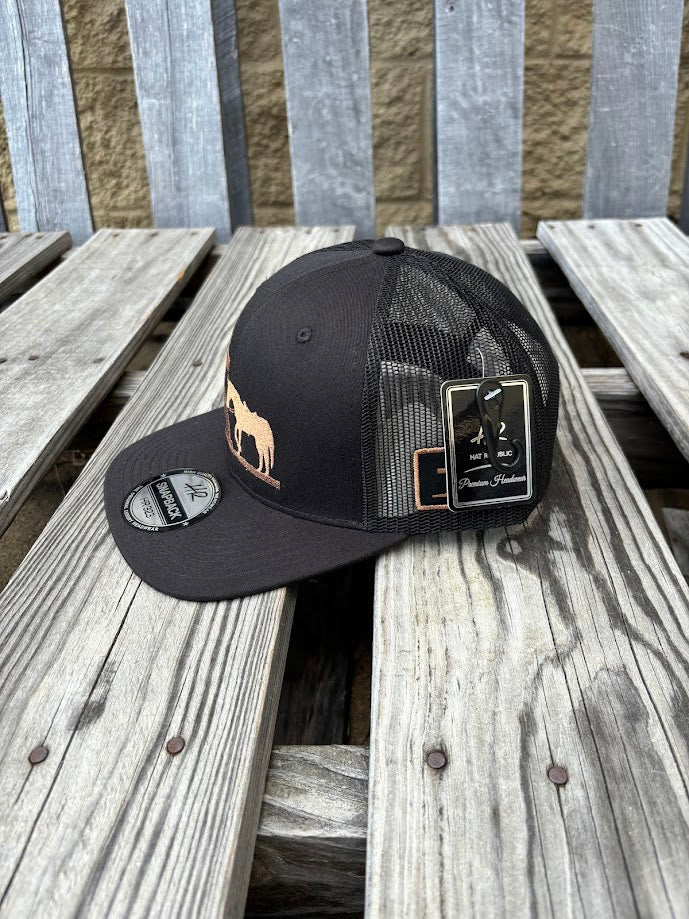 A black snapback cap with a embroidered praying cowboy design. Side View