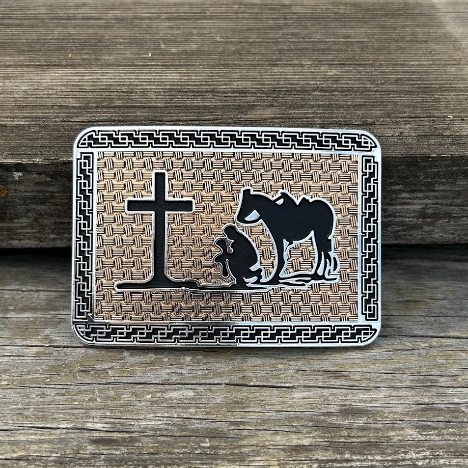This silver, gold, and black buckle features a Praying Cowboy design on a gold rectangle featuring Black accents and a intricate silver border. Front View