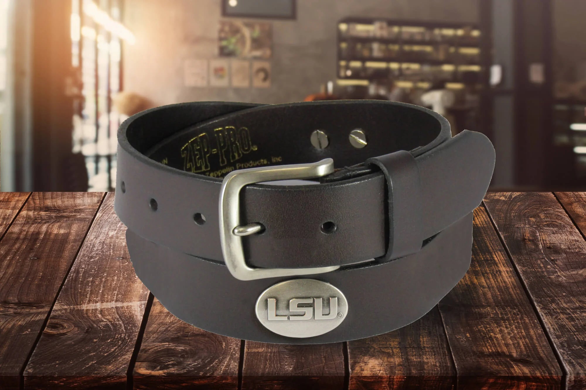 A Zep-Pro brown leather belt rolled up to show a silver metal buckle and an oval LSU silver tone concho.