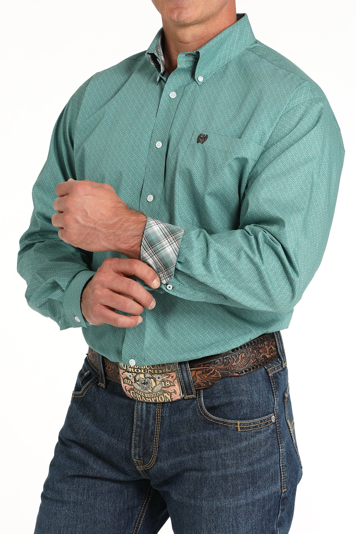 Teal print Cinch button-down long sleeve shirt showing contrast green plaid cuff lining, 2-button cuffs, embroidered pocket logo. Also showing jeans with a belt on model. Front angled view.