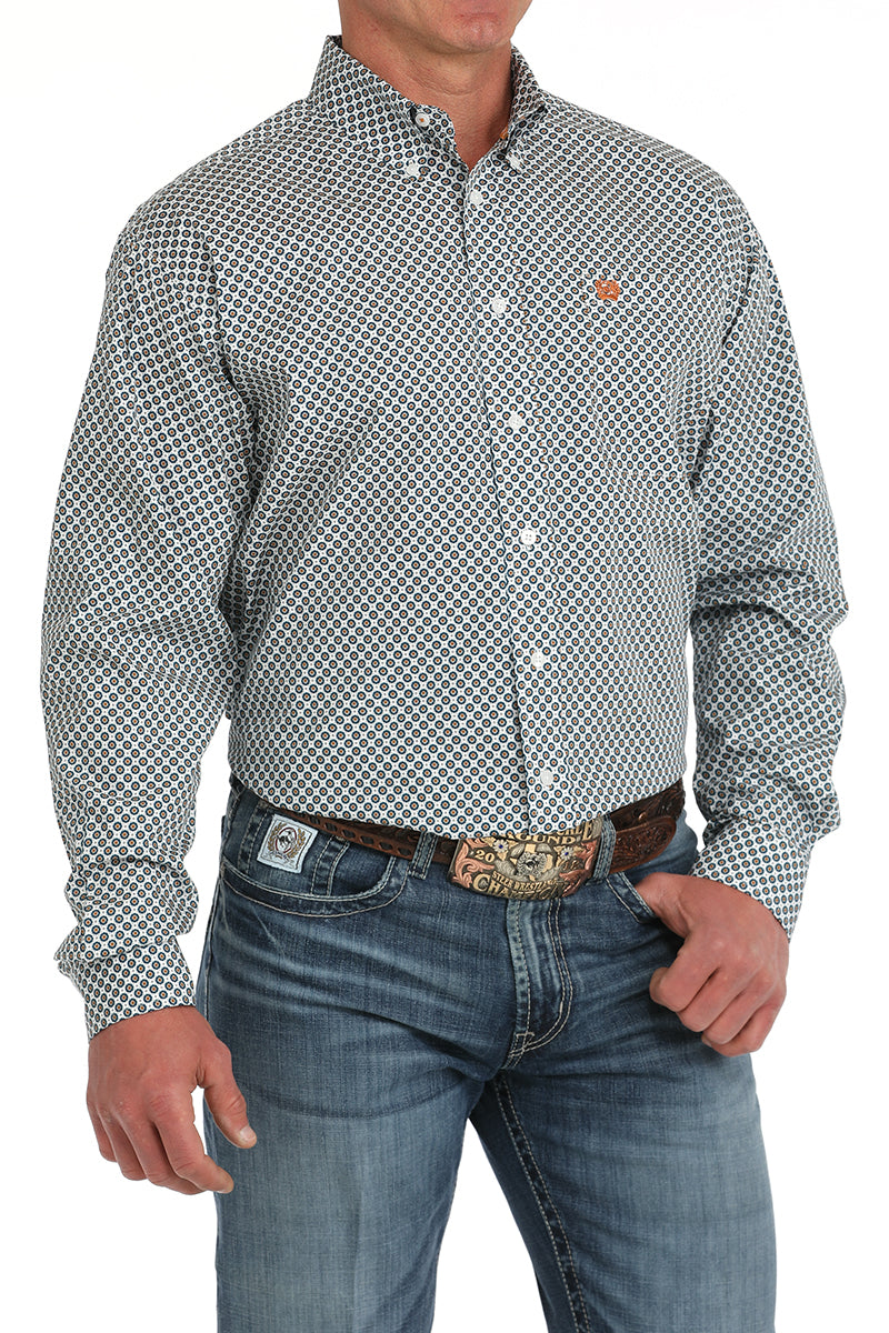 Man wearing a Cinch white print long sleeve button down shirt with left chest pocket and jeans with a belt and buckle. Front view.