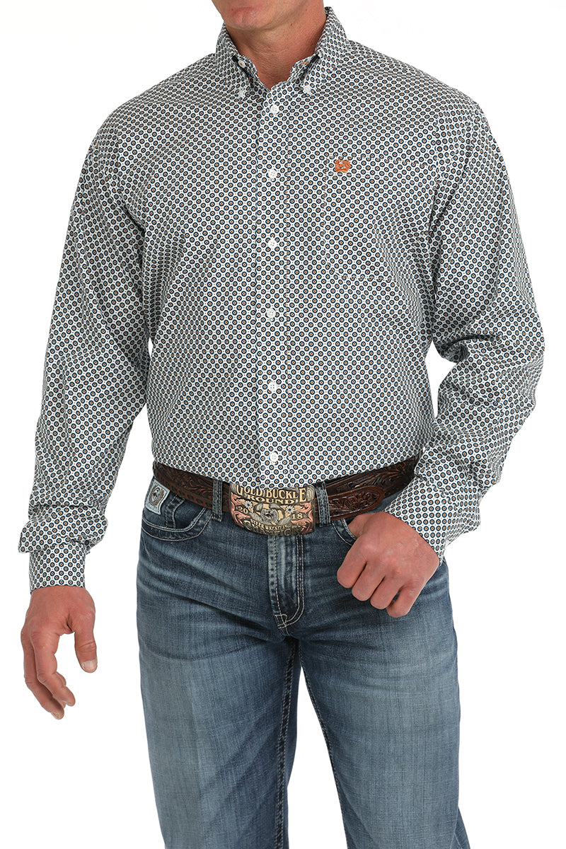 Man wearing a Cinch white print long sleeve button down shirt with left chest pocket and jeans with a belt and buckle. Front view.