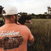 Lifestyle photo of dog and young man wearing Fieldstone branded Salmon colored Comfort Color short sleeve pocket graphic t-shirt with pointer dog on back