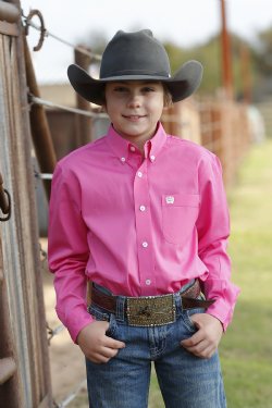 A boy wearing a hot pink long sleeve button down shirt with an embroidered logo on the pocket.