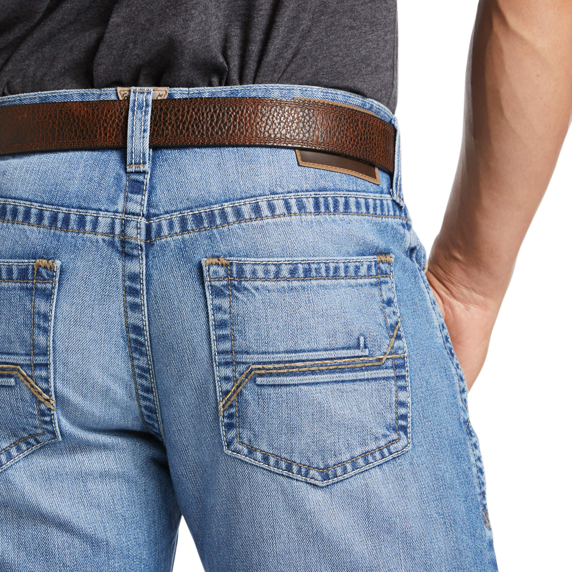 Men's Ariat M4 relaxed fit boot cut jean in a light wash. Close up view of back pocket stitching details.