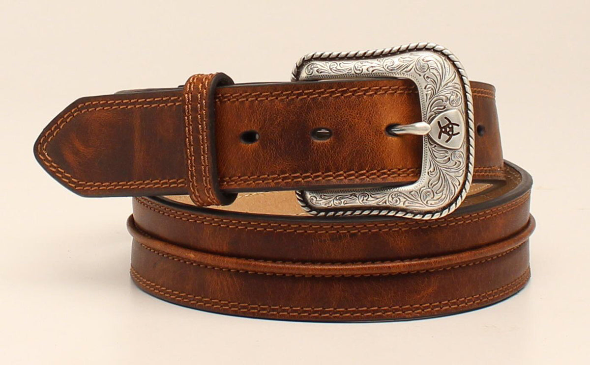 Men's brown western belt with distressed leather and a detailed silver buckle featuring the Ariat logo.