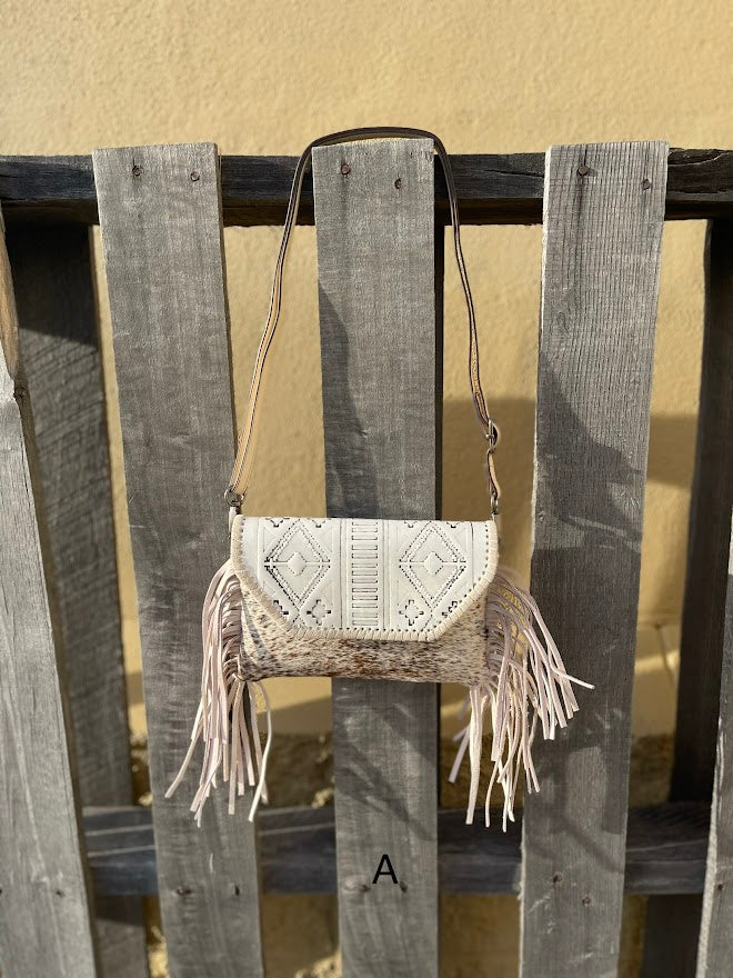 This cowhide and Beige leather bag features fringe sides and can be used as a wristlet or crossbody. It has a geometric print debossed flap with a whipstitch border. Front View A