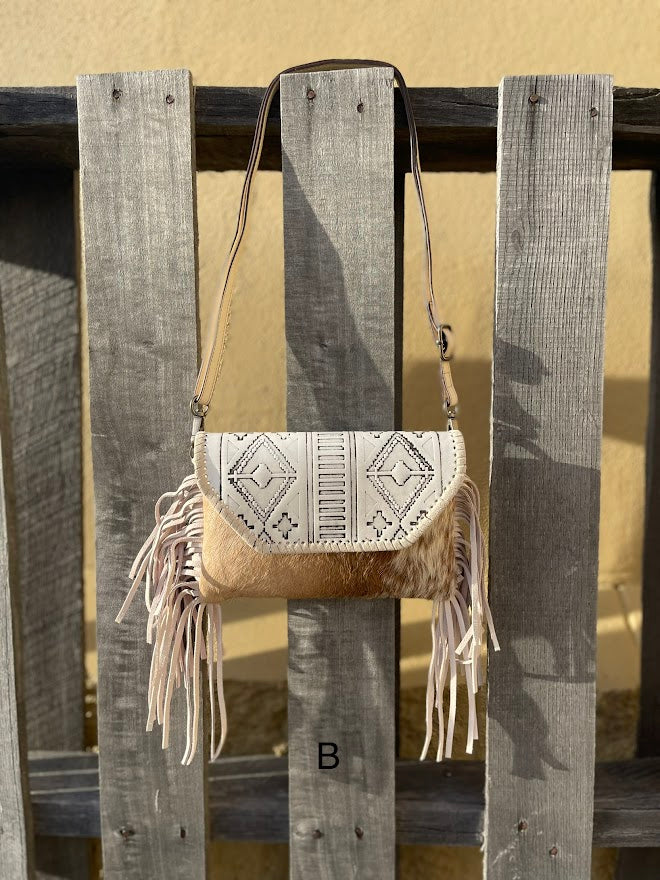 This cowhide and Beige leather bag features fringe sides and can be used as a wristlet or crossbody. It has a geometric print debossed flap with a whipstitch border. Front View B