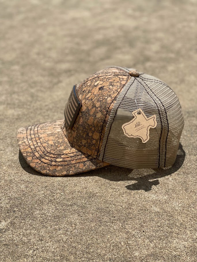A brown cork cap with an metal American flag Concho on the front, featuring an adjustable fit mesh back. Side View