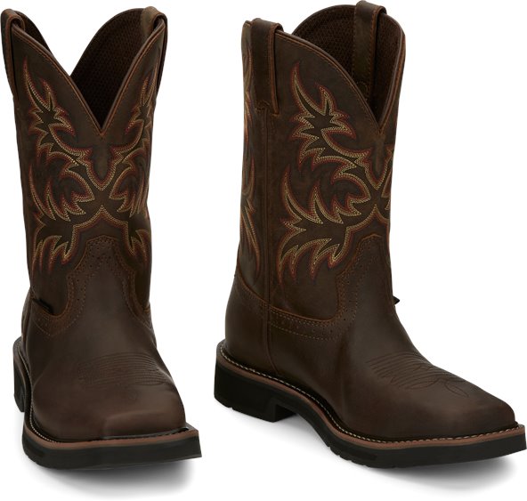 A profile view pair of Justin Men's 11" Steel Toe Driller work boots in rugged tan color with a square toe style and decorative stitching.
