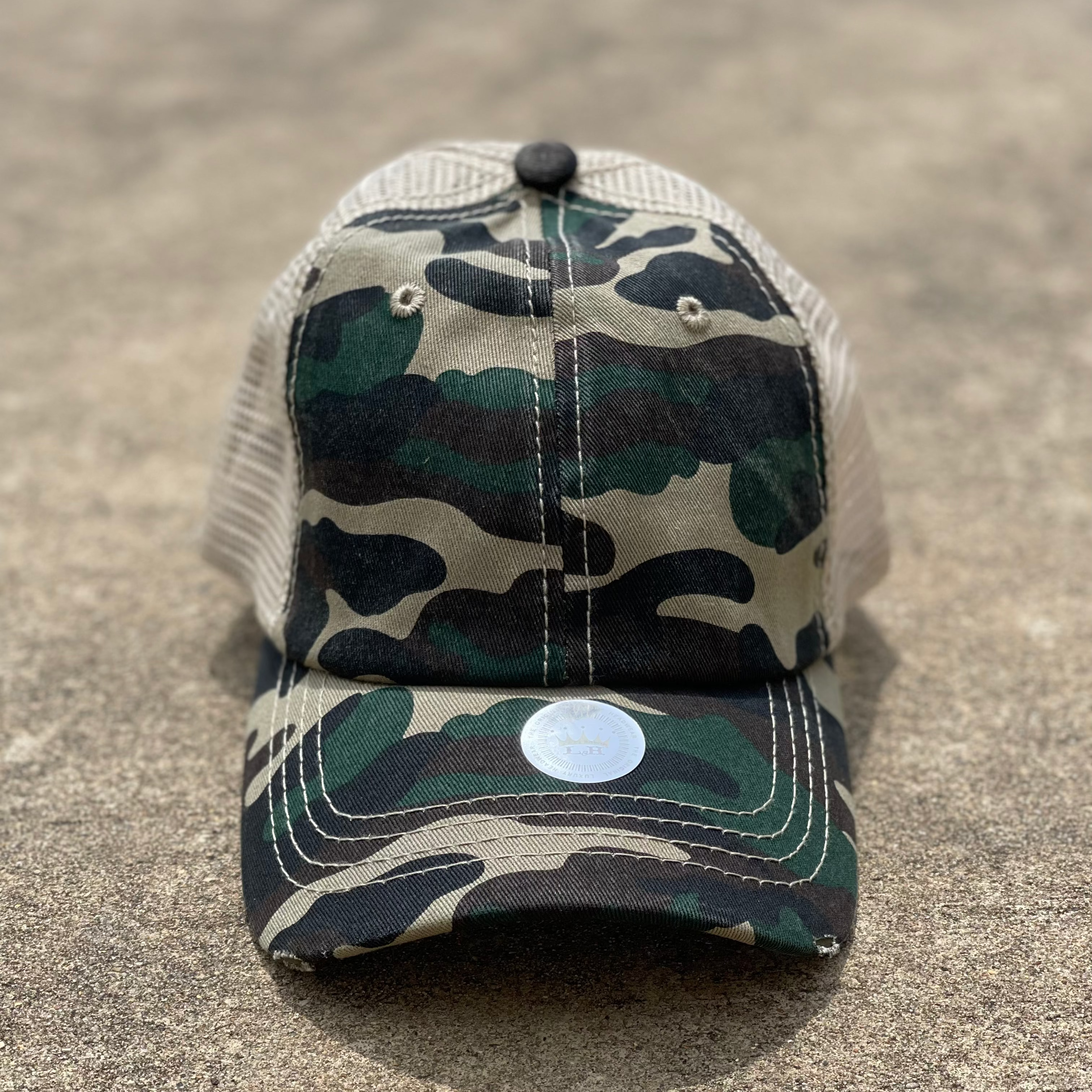 Camo front and tan mesh back distressed crisscross ponytail cap. The back has elastic crisscrossing bands and a adjustable Velcro back for a truly adjustable fit for your ponytails or buns. Front View