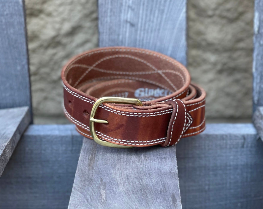An oil-dipped brown leather work belt with white figure 8 stitching and a brass buckle. Front view.