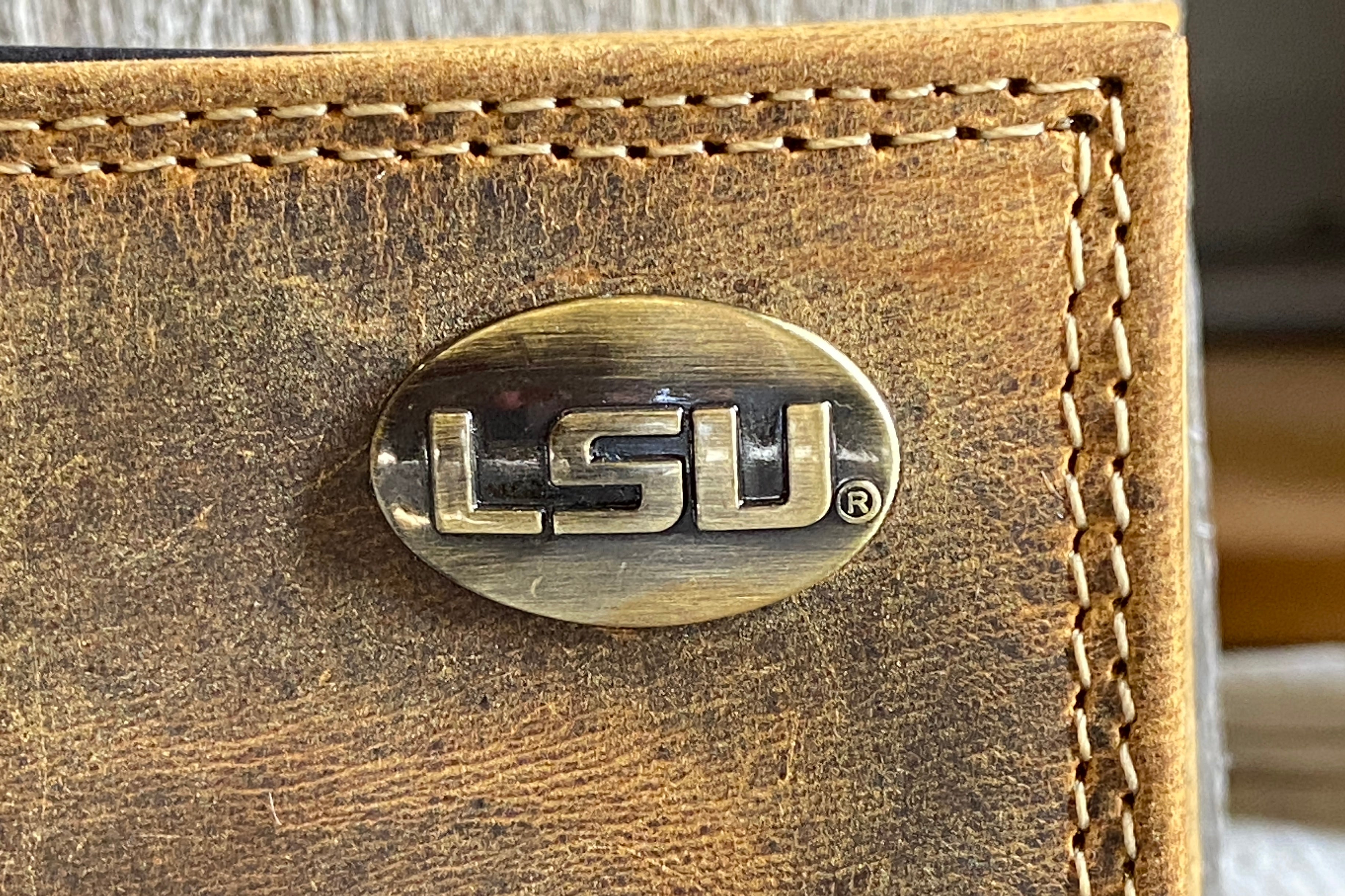 Zep Pro Louisiana State University Tigers Vintage Tan Leather Tri-fold Wallet closeup front view showing LSU brass concho detail.