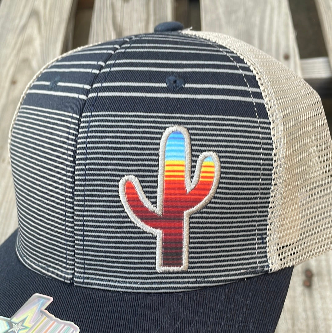 Navy and Grey trucker cap with a striped pattern featuring a cactus patch design on the front, solid Navy bill, Grey mesh back. Close up view of cactus patch.