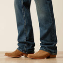 Men's Ariat M4 relaxed fit boot cut jeans in a medium wash. Bottom view showing leg opening over boots. 
