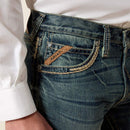Men's Ariat M5 slim fit straight leg jean in a medium wash. Close up view of front pocket stitching details and slanted Ariat logo tag. 