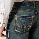Men's Ariat M5 slim fit straight leg jean in a medium wash. Rear pocket showing stitching details and Ariat logo tag. 