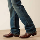 Men's Ariat M5 slim fit straight leg jean in a medium wash. Bottom view showing leg opening over jeans. 