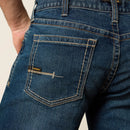 Men's Ariat M4 Rebar relaxed fit boot cut work jeans in a dark wash. Rear view showing back pocket stitching details and Ariat logo tag. 