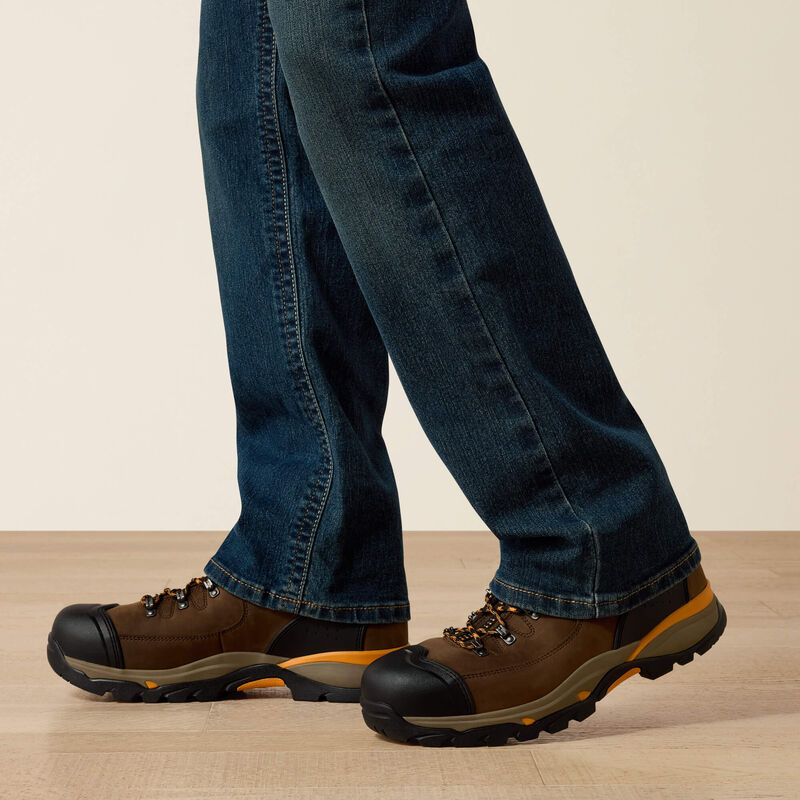 Men's Ariat M4 Rebar relaxed fit boot cut work jeans in a dark wash. Bottom view showing leg opening over boots. 
