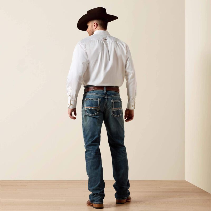 Men's Ariat M4 relaxed fit boot cut jeans in a medium wash. Rear view showing jeans on model.