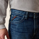 Men's Ariat M4 relaxed fit boot cut FR jeans. Close up view of front pocket showing stitching details and slanted Ariat FR tag. 