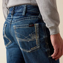 Men's Ariat M4 relaxed fit boot cut FR jeans. Rear view showing stitching details on pockets and Ariat FR logo tag. 