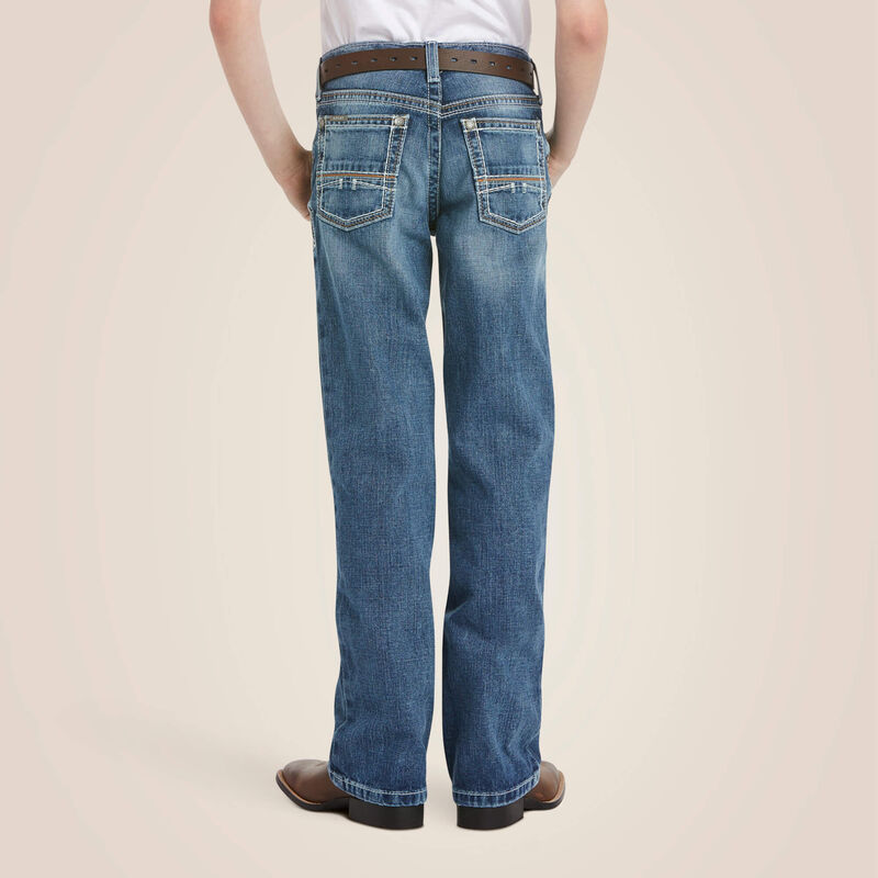Boys Ariat B4 relaxed fit boot cut jeans in a medium wash. Rear view showing stitching details on back pockets. 
