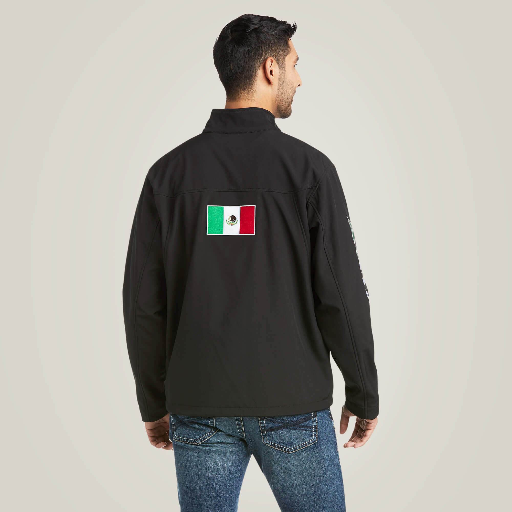 Men's Ariat softshell Team logo jacket in black with a blocked Ariat logo in white, green, and red representing the Mexican Flag. Full rear view showing jacket length. 