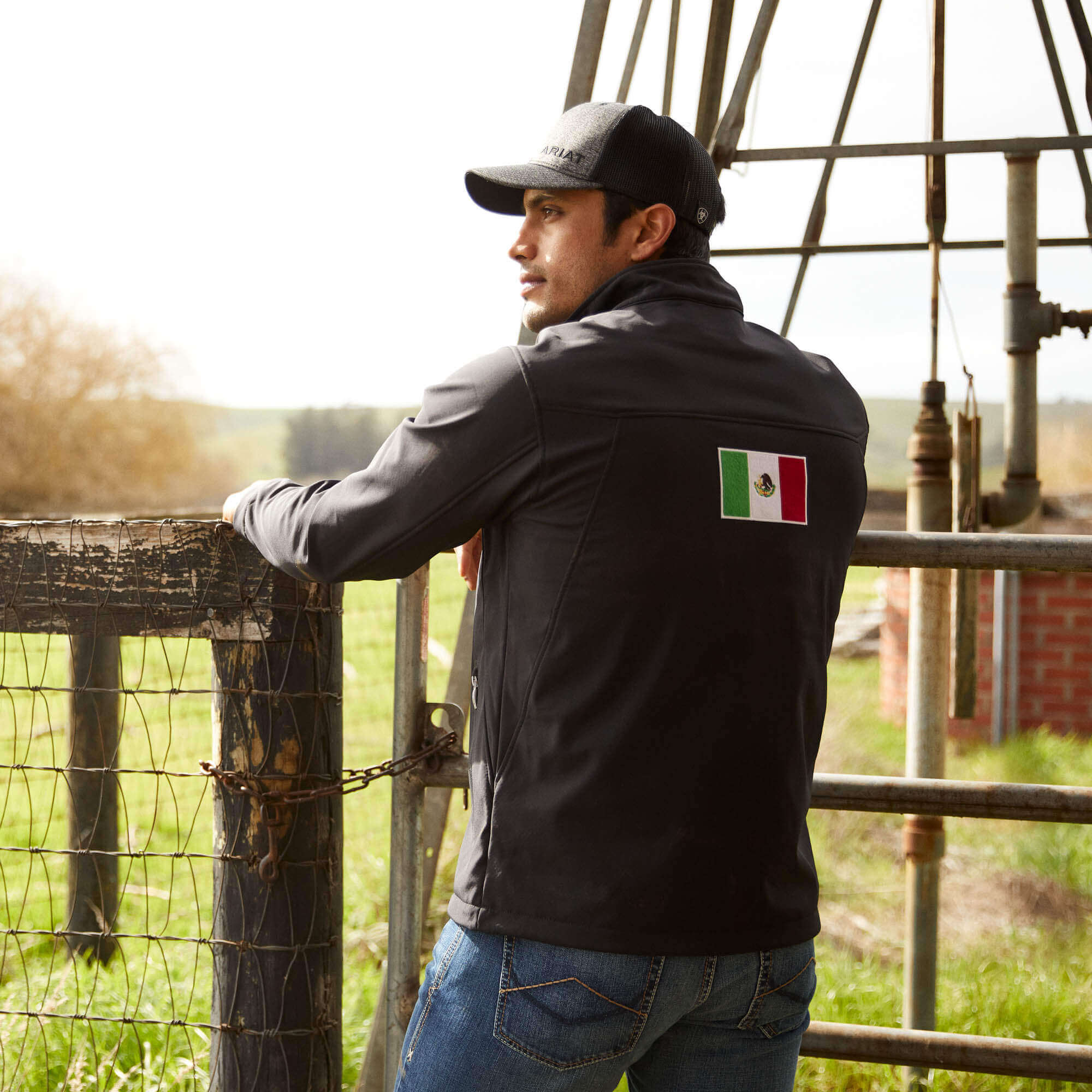 Men's Ariat softshell Team logo jacket in black with a blocked Ariat logo in white, green, and red representing the Mexican Flag. Rear view 