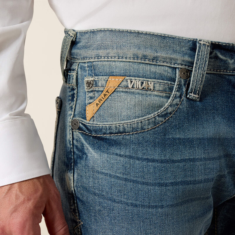 Men's Ariat M7 slim fit straight leg jeans in a light wash. Close up of pocket details showing slanted Ariat logo tag. 
