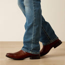 Men's Ariat M7 slim fit straight leg jeans in a light wash. Bottom view showing jeans opening over boots. 