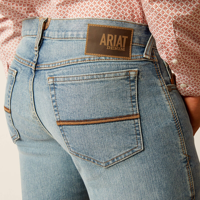 Men's Ariat M7 straight jean in a light wash. Rear view showing back pocket stitching and Ariat Denim logo patch. 