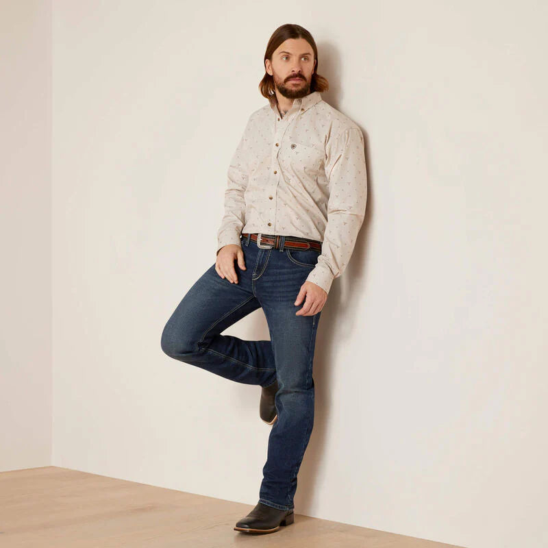 Men's Ariat long sleeve button down shirt in Bandshell, a tan color with a print of steer skulls. Full front view showing shirt tucked in. 