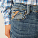 Boy's Ariat relaxed fit boot cut jeans in a medium wash. Close up of front pocket showing Ariat logo tag. 