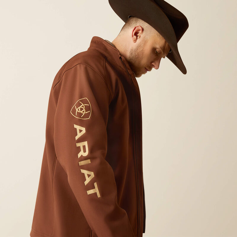 Men's Ariat softshell jacket in Potting Soil. Side view showing bold Ariat logo on left arm. 
