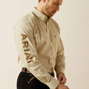 Men's Ariat long sleeve shirt in a Cream/Light Brown pattern. Shirt features button close and a bold Ariat logo on left sleeve. Close up of left sleeve logo. 