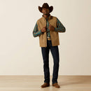 Men's Ariat khaki vest with full front zipper with wind stop lining, left chest Ariat logo, zippered hand pockets, and standing collar. Shows solid yoke and chest with tonal geometric lower body and sleeves. Hits mid hip. . Full front view.