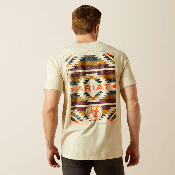 The model is  wearing a natural-colored t-shirt with a geometric Southwestern pattern and 'Ariat' branding on the back.