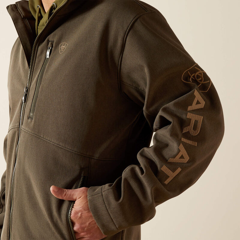 Ariat men's softshell jacket in Earth Green Heather. This jacket features a bold Ariat logo on the left sleeve in brown. Close up of left sleeve showing Ariat logo in brown. 