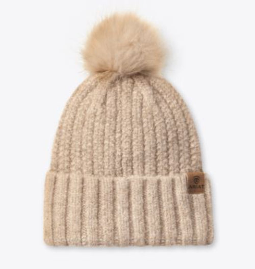 Beige knit beanie with a fur pom-pom with small Ariat logo leather patch on band.